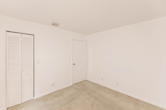 unfurnished bedroom with light colored carpet and a closet