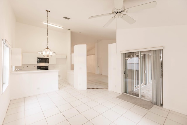 tiled spare room featuring lofted ceiling and ceiling fan with notable chandelier