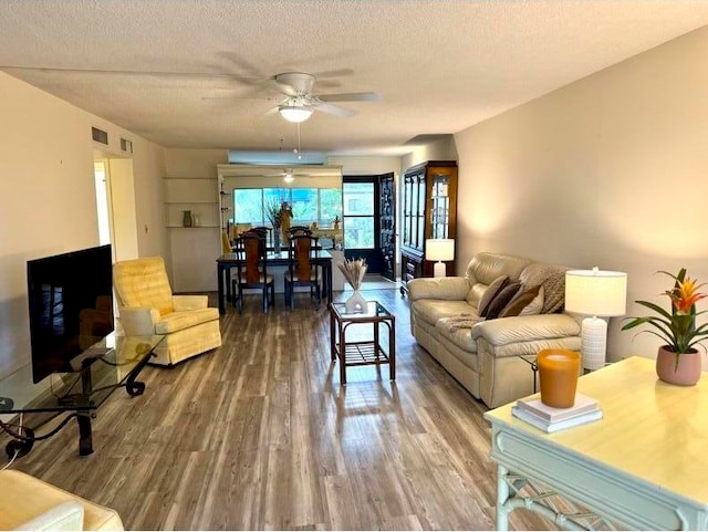 living room featuring ceiling fan, wood-type flooring, and a textured ceiling