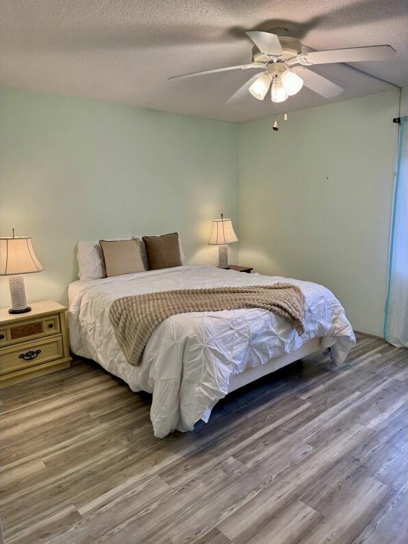 bedroom featuring hardwood / wood-style floors, ceiling fan, and a textured ceiling