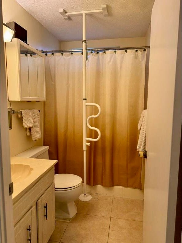 bathroom featuring vanity, a textured ceiling, tile patterned floors, and toilet