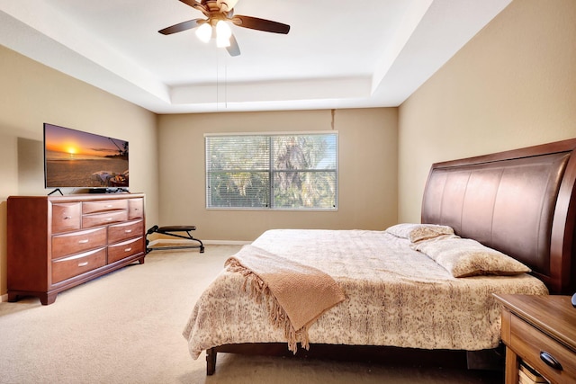 bedroom with light carpet, a tray ceiling, and ceiling fan