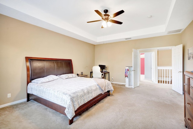 carpeted bedroom with a tray ceiling and ceiling fan