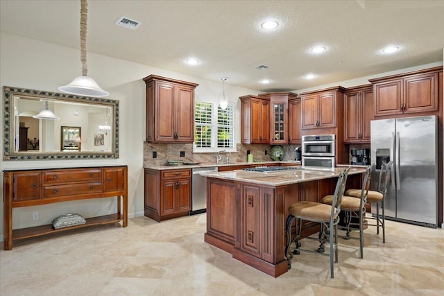 kitchen with a breakfast bar, hanging light fixtures, light stone countertops, appliances with stainless steel finishes, and a kitchen island