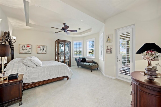 carpeted bedroom featuring ceiling fan, a tray ceiling, access to outside, and multiple windows