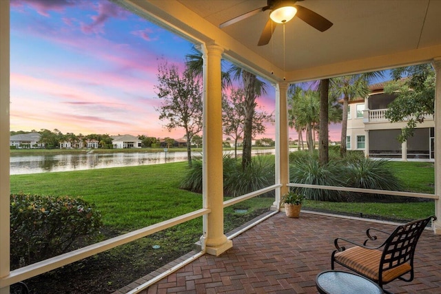 sunroom featuring ceiling fan and a water view