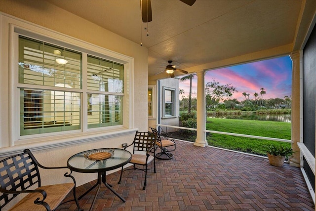 sunroom / solarium featuring ceiling fan and a water view