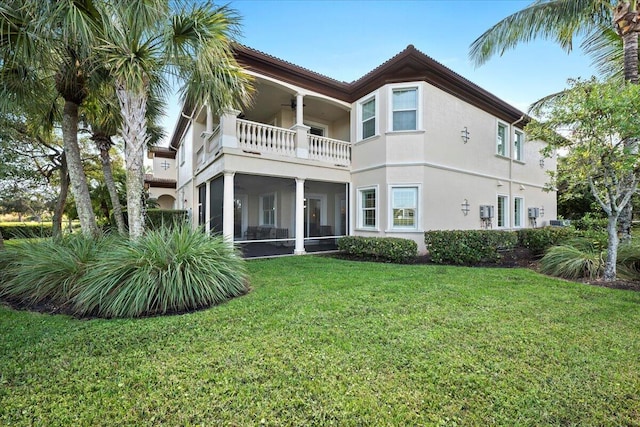 back of house with a yard, a balcony, and a sunroom