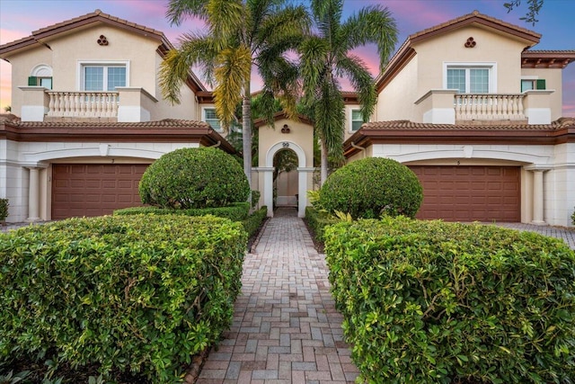 mediterranean / spanish-style home featuring a garage and a balcony