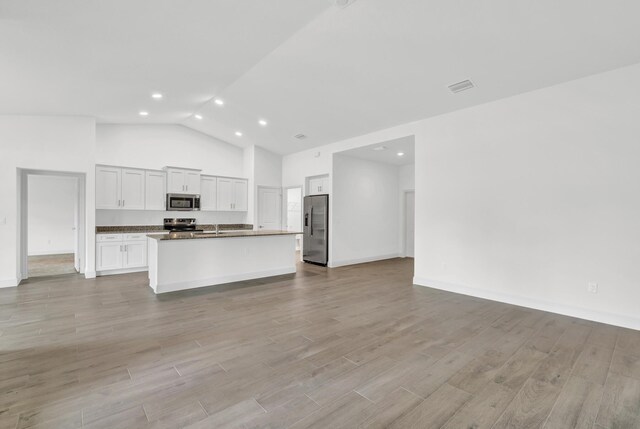 kitchen with white cabinets, light wood-type flooring, vaulted ceiling, and appliances with stainless steel finishes