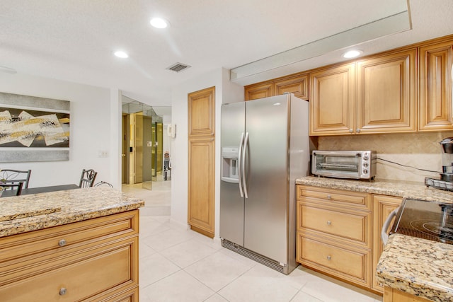 kitchen featuring decorative backsplash, light stone counters, stainless steel fridge with ice dispenser, and light tile patterned floors