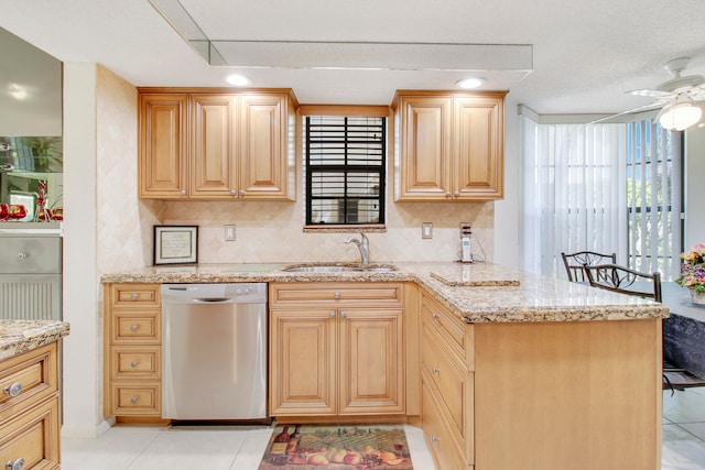 kitchen with light stone counters, sink, light tile patterned floors, and stainless steel dishwasher