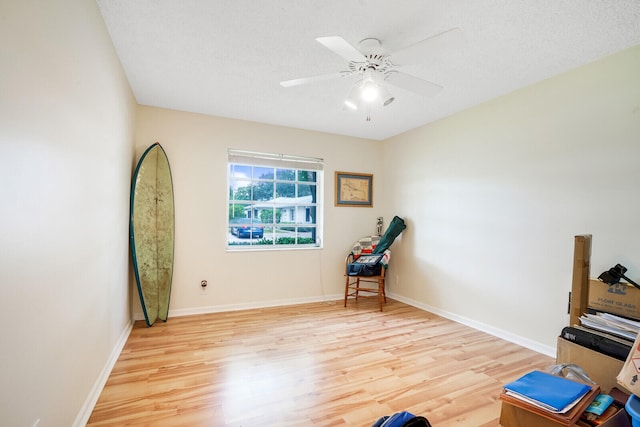 living area featuring ceiling fan, a textured ceiling, and light wood-type flooring