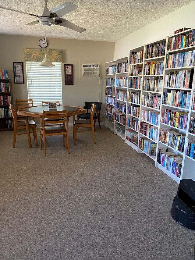 dining area with carpet flooring, ceiling fan, an AC wall unit, and a textured ceiling