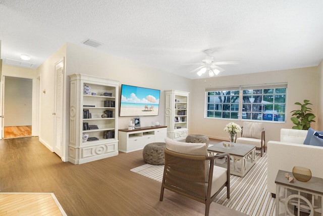 living room with ceiling fan, light hardwood / wood-style floors, and a textured ceiling