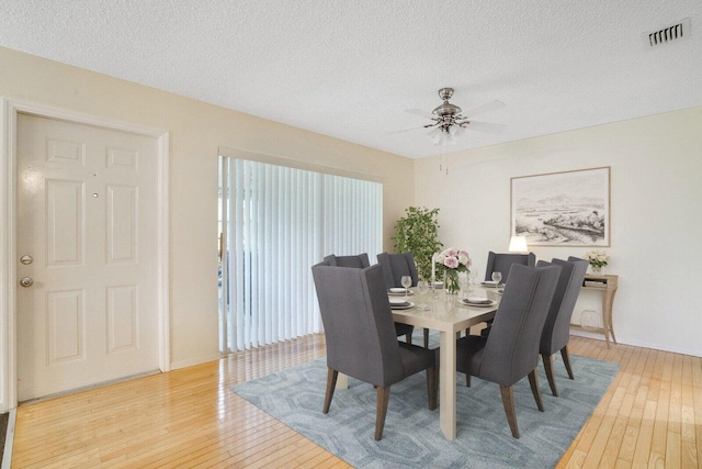 dining space with a textured ceiling, light hardwood / wood-style flooring, and ceiling fan