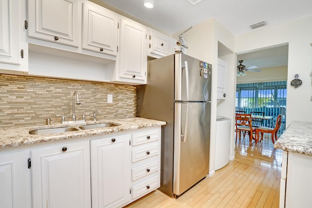 kitchen with white cabinetry, sink, and stainless steel refrigerator