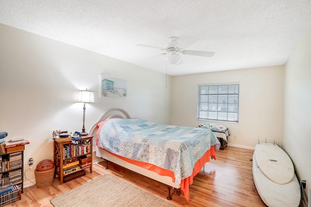 bedroom with hardwood / wood-style floors, a textured ceiling, and ceiling fan