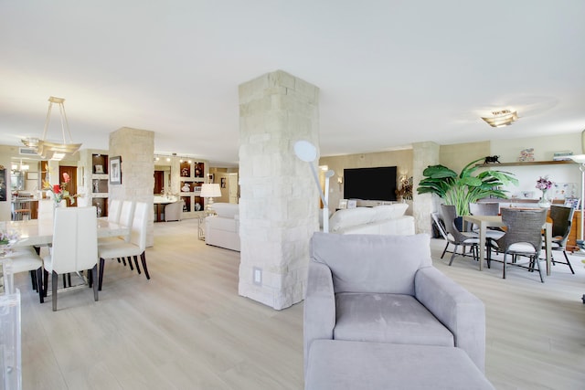 living room featuring light wood-type flooring and decorative columns