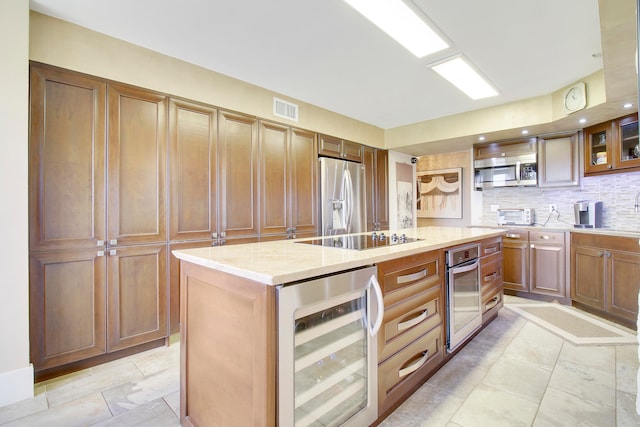 kitchen featuring decorative backsplash, light stone counters, stainless steel appliances, a center island, and wine cooler