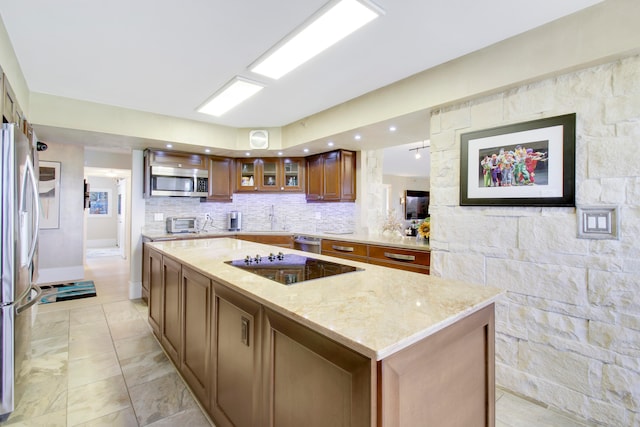 kitchen with a center island, light stone counters, stainless steel appliances, and tasteful backsplash