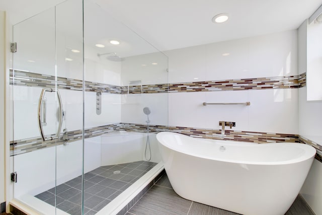 bathroom featuring plus walk in shower, tile patterned floors, and tile walls