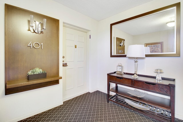 carpeted foyer entrance with a textured ceiling