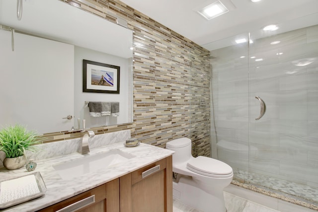 bathroom featuring vanity, toilet, tile walls, tasteful backsplash, and a shower with shower door