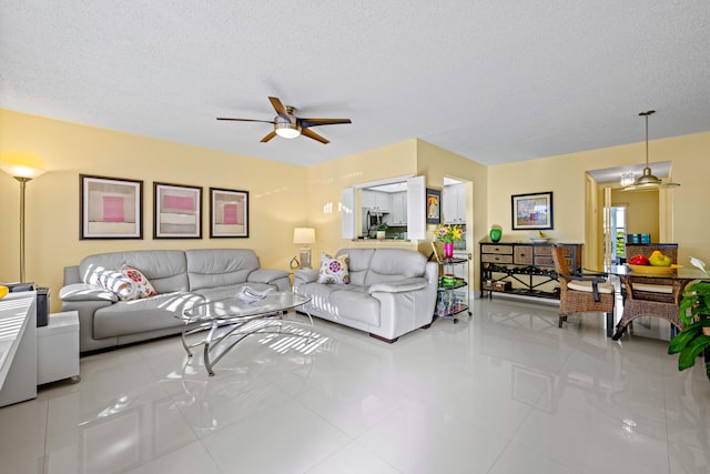 living room featuring ceiling fan, light tile patterned floors, and a textured ceiling