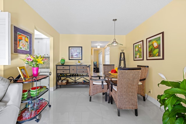 dining space featuring light tile patterned flooring and a textured ceiling