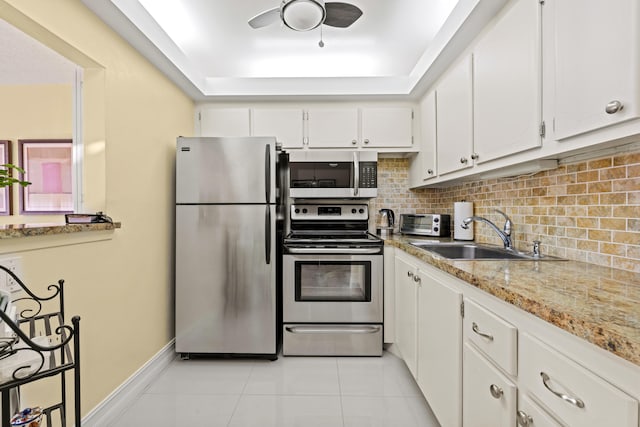 kitchen with white cabinets, sink, tasteful backsplash, light stone counters, and stainless steel appliances