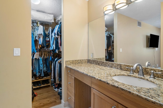 bathroom with vanity, wood-type flooring, and a textured ceiling