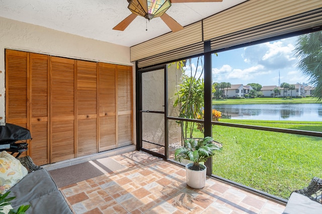 unfurnished sunroom with ceiling fan and a water view