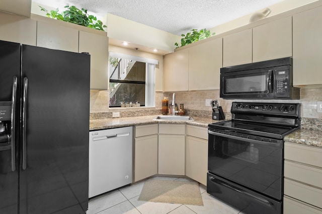 kitchen featuring decorative backsplash, sink, black appliances, light tile patterned floors, and cream cabinetry