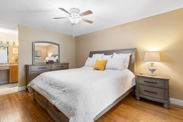 bedroom featuring a textured ceiling, light wood-type flooring, ceiling fan, and connected bathroom