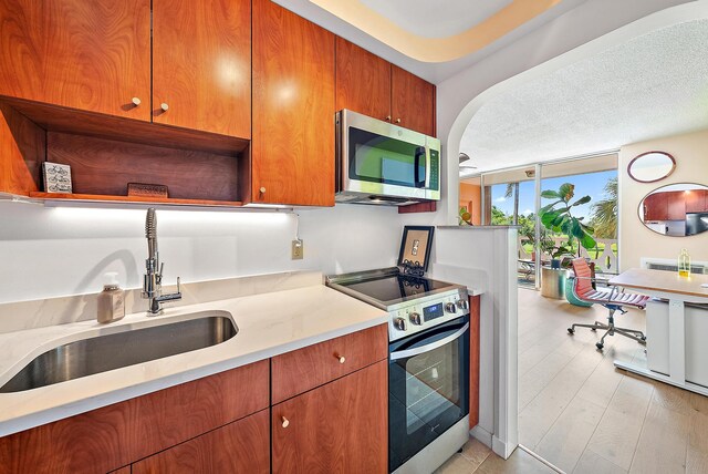 kitchen with floor to ceiling windows, sink, a textured ceiling, and appliances with stainless steel finishes