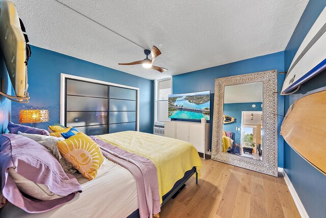 bedroom with a closet, ceiling fan, light hardwood / wood-style flooring, and a textured ceiling