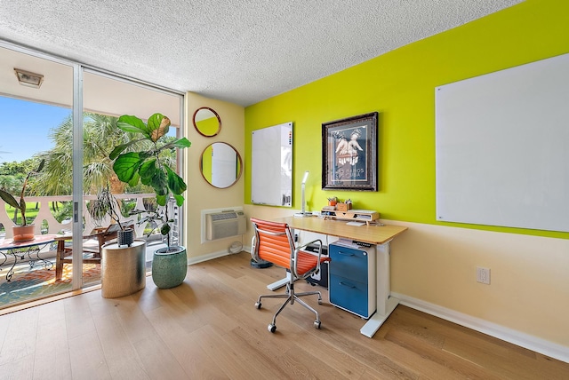 home office with expansive windows, a textured ceiling, light hardwood / wood-style floors, and a wall mounted AC