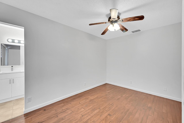 spare room featuring a textured ceiling, light hardwood / wood-style flooring, ceiling fan, and sink