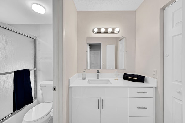 full bathroom featuring combined bath / shower with glass door, toilet, a textured ceiling, and vanity