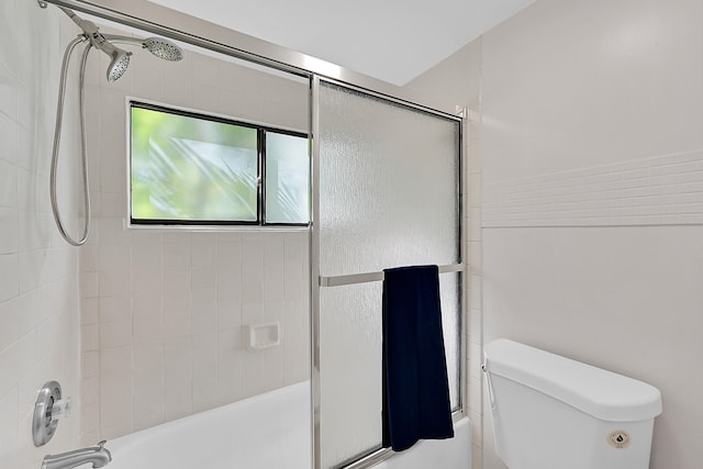 bathroom with toilet and shower / bath combination with glass door