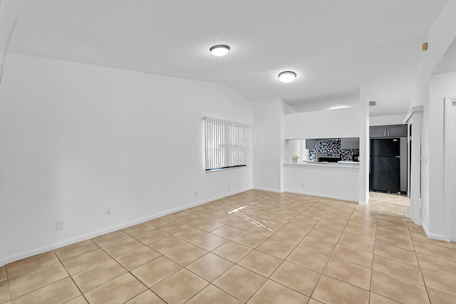 unfurnished living room featuring light tile patterned floors and vaulted ceiling