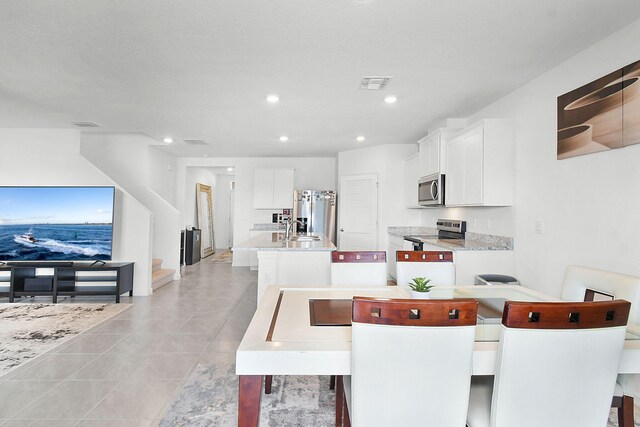 dining space featuring light tile patterned flooring, a textured ceiling, and sink