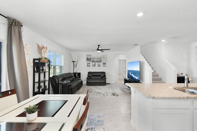 living room with light tile patterned floors, ceiling fan, and sink