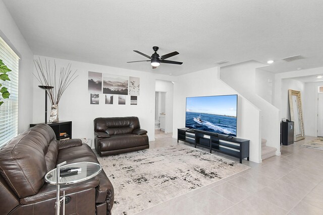 living room with ceiling fan, light tile patterned floors, and a textured ceiling