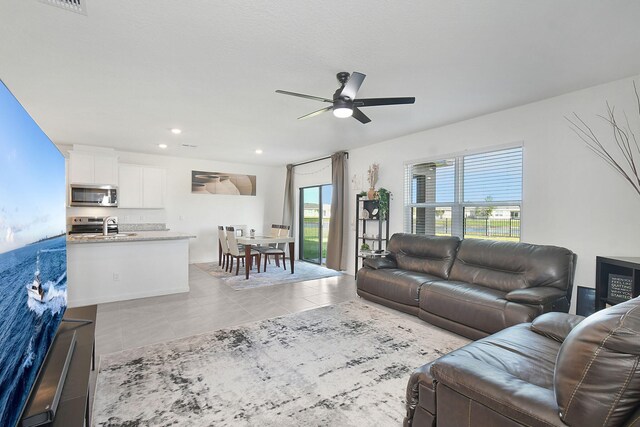 tiled living room with ceiling fan, sink, and a wealth of natural light