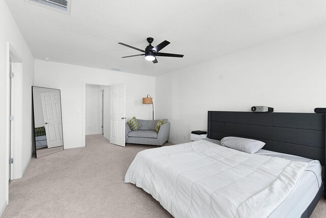 bedroom with a textured ceiling, ceiling fan, and light carpet