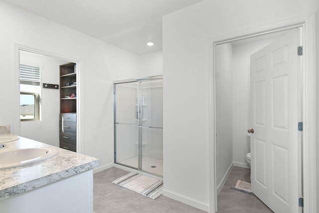 bathroom featuring toilet, tile patterned flooring, vanity, and walk in shower