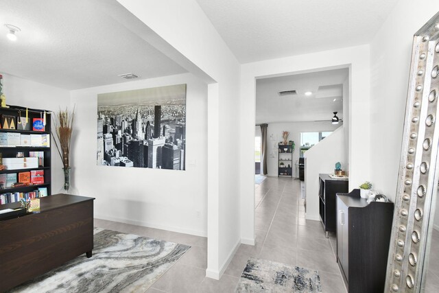 corridor with light tile patterned floors and a textured ceiling