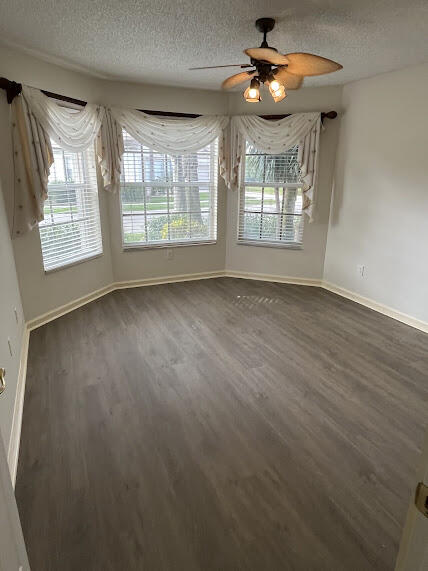 unfurnished dining area with ceiling fan, dark wood-type flooring, and a textured ceiling